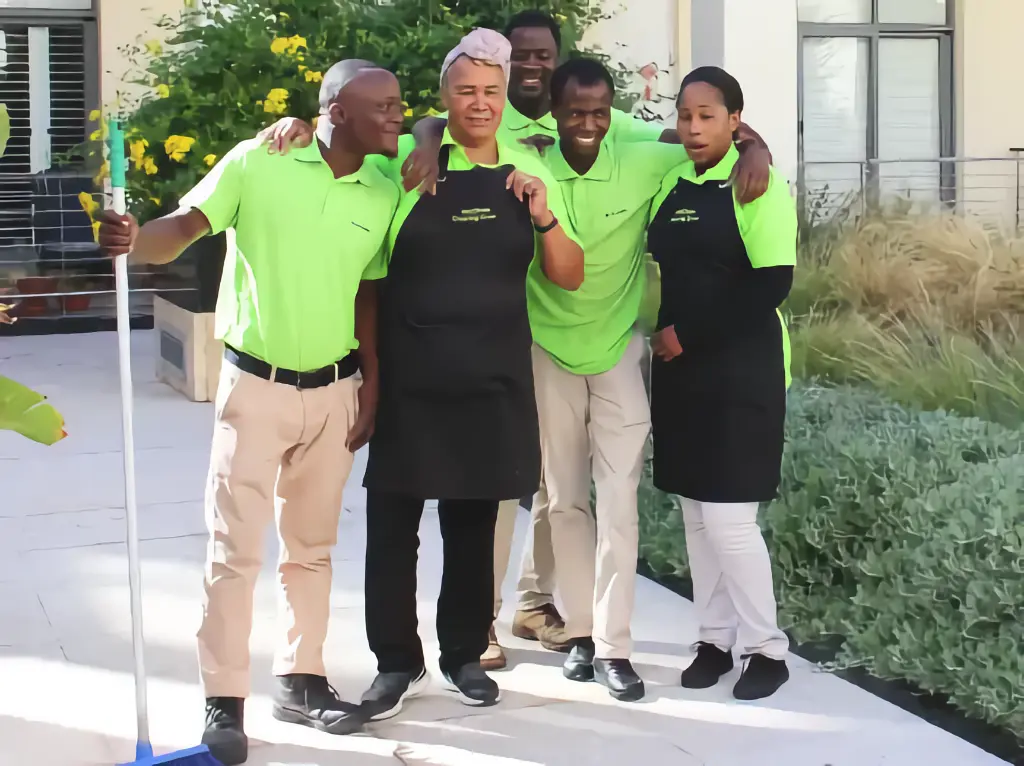 A cleaning team huddling and smiling happily