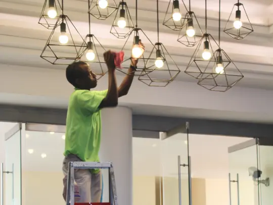 man deep cleaning light fittings in lobby