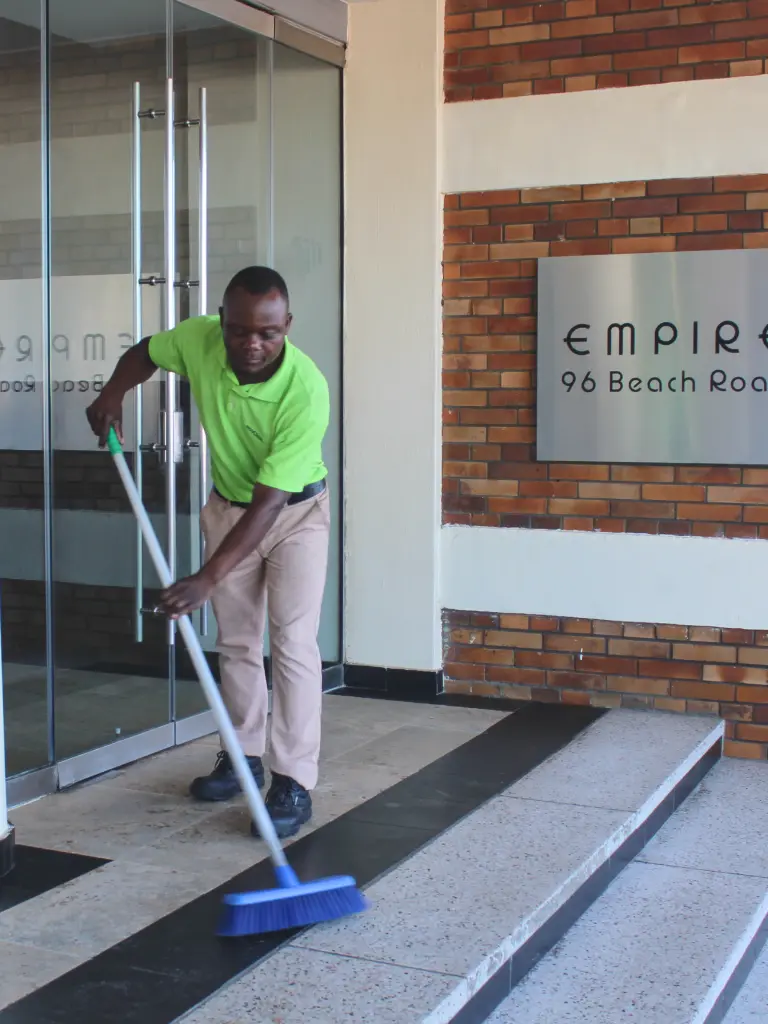 man sweeping steps in front of building
