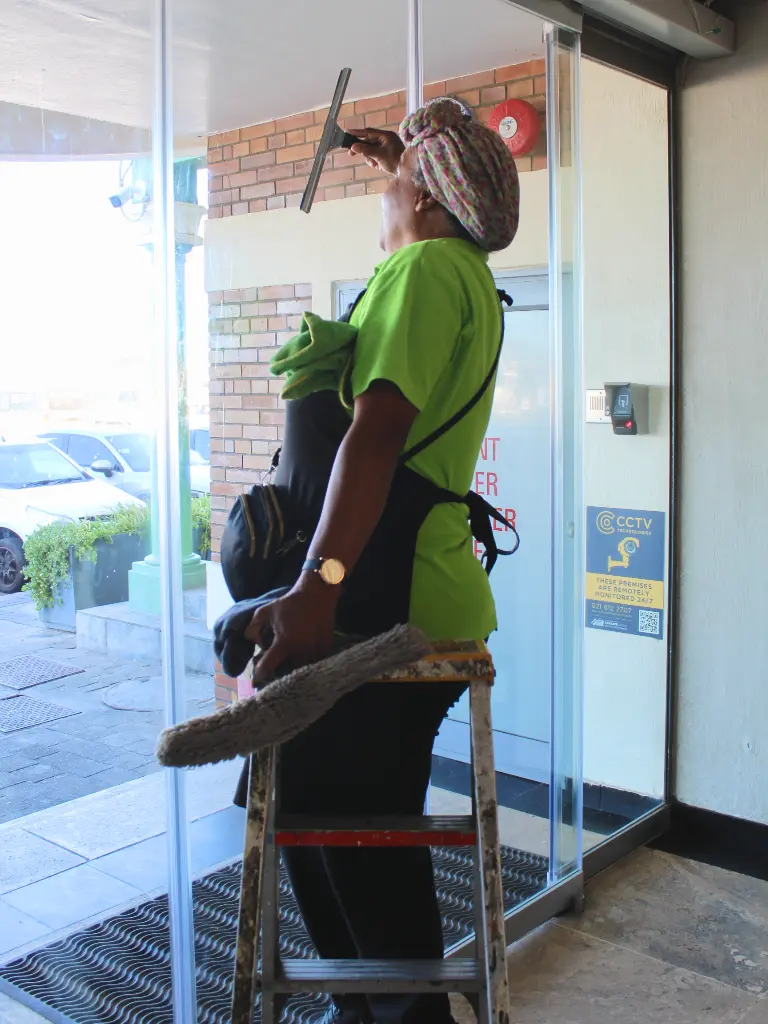 woman cleaning glass doors of entrance way to building